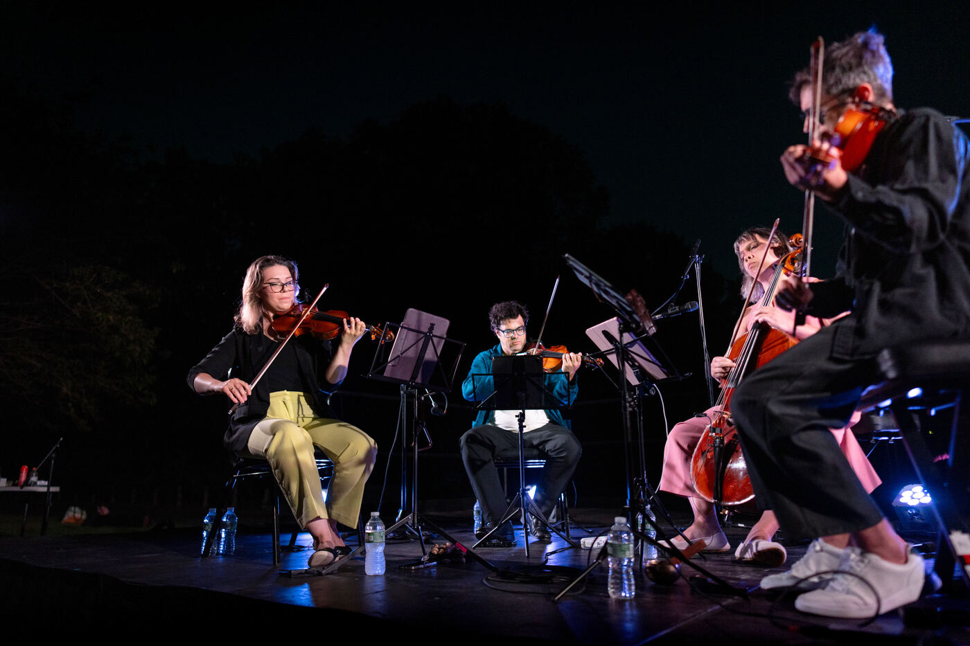 The Attacca Quartet performing on stage at night.
